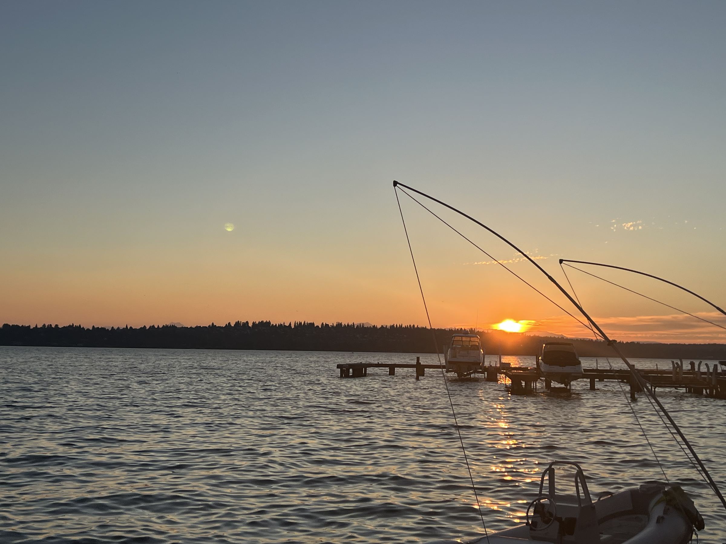 Sunset over a lake, with boat lifts silhouetted against the water